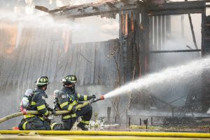 firefighter sprays water on burning house from the Texas Panhandle wildfires that have been spreading